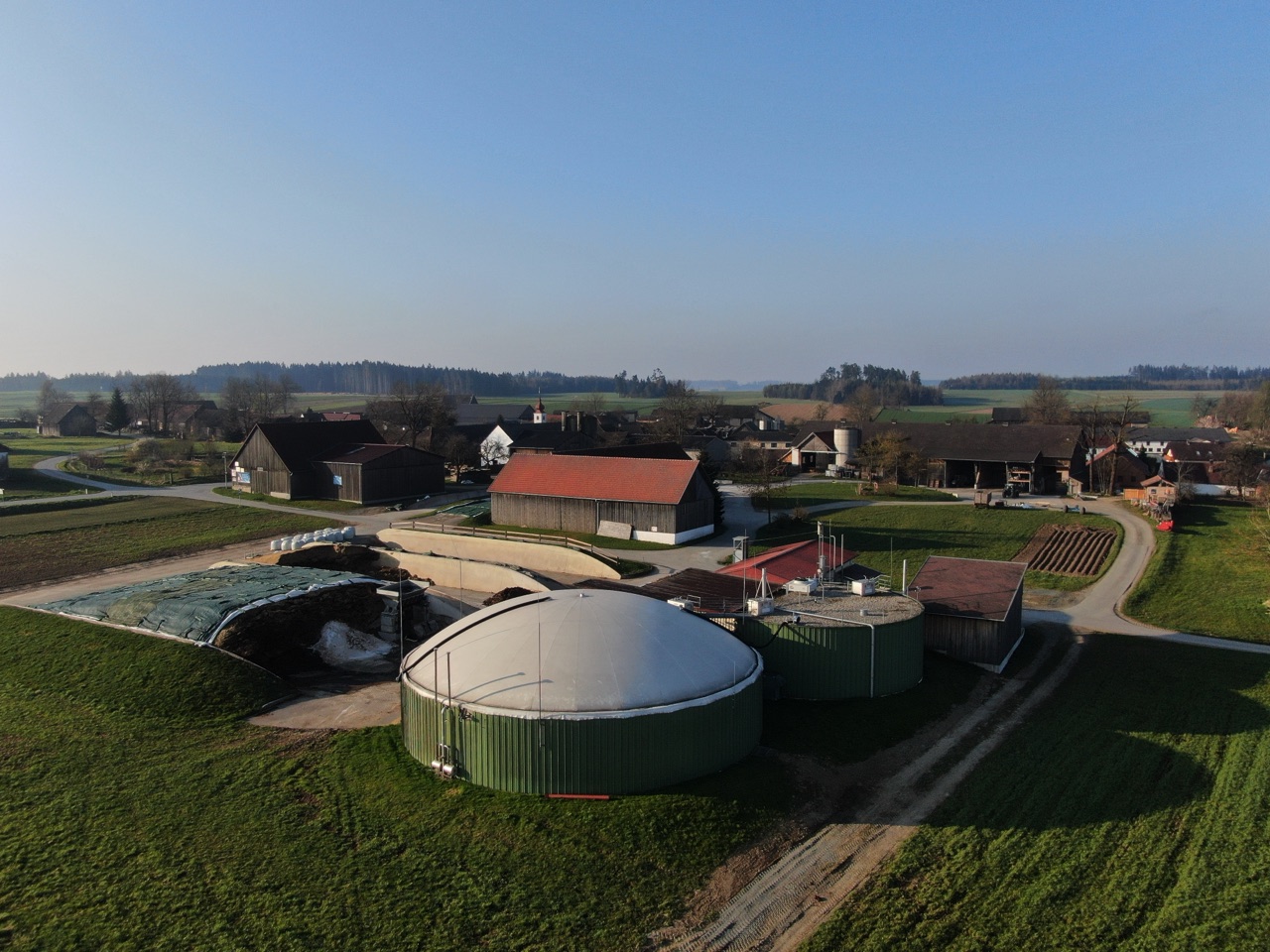 Luftaufnahme der Biogasanlage des Biohofs Hirnschall mit Fermenter und Feldern